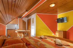 - une chambre avec des murs orange et jaune et un lit dans l'établissement Apartments and Rooms Hodnik Slavko, à Bohinj