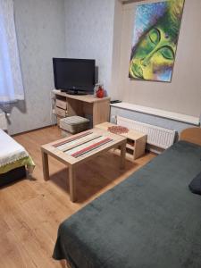 a living room with a coffee table and a tv at Kambario nuoma su bendru vonios kambariu in Kaunas