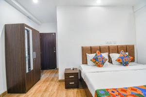 a bedroom with two beds and a wooden cabinet at FabHotel Seven Wonders 55 in kolkata