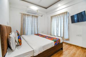 a bedroom with a bed and a large window at FabHotel Seven Wonders 55 in kolkata