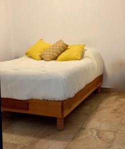 Una cama con almohadas amarillas encima. en Suites Apodaca, en Monterrey