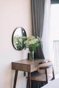 een tafel met een spiegel en een vaas met bloemen bij Canary Dalat Hotel in Da Lat