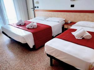 two beds in a hotel room with towels on them at Ben Hur Rimini in Rimini