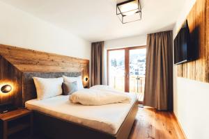 a bedroom with a bed with a wooden headboard at Burgstadl Aparthotel & Restaurant in Ladis