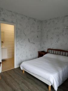 a bedroom with a white bed and a marble wall at La Cremaillere in Miremont