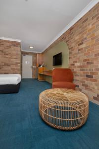 een kamer met een stoel, een bank en een tv bij All Seasons Motel Armidale in Armidale