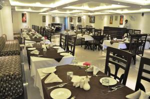 a dining room with tables and chairs with white plates at Hotel Mandakini Royale in Kānpur