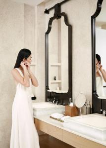 a woman in a white dress talking on a cell phone in a bathroom at Dusit Thani Bangkok in Bangkok