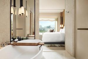 a bathroom with a tub and a bedroom with a bed at Dusit Thani Bangkok in Bangkok