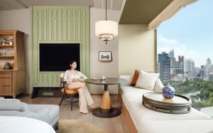 a woman sitting at a table in a living room at Dusit Thani Bangkok in Bangkok