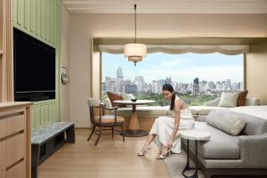 a woman sitting in a room with a view of a city at Dusit Thani Bangkok in Bangkok