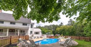 a house with a swimming pool with chairs around it at Cranmore Mountain Lodge Bed & Breakfast in North Conway