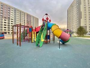 um parque infantil com escorrega num parque de estacionamento em Однокомнатные апартаменты ЖК Auezov city 37 em Almaty