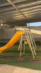 a yellow slide with a ladder on the grass at Alzam Residency in Nizwa