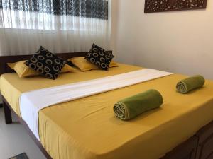 uma cama com duas almofadas verdes em cima em The Esence of Sri Lanka em Ahungalla