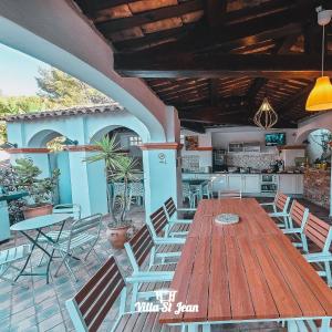 an outdoor patio with a wooden table and chairs at Villa Mas de la Mer in La Ciotat