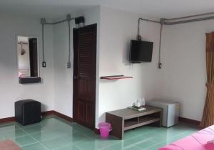 a room with a bed and a tv and a table at Smile Buffalo Resort สไมล์ รีสอร์ท in Ban Lum Phen