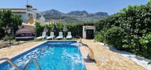 a swimming pool in a yard with chairs and a house at Cortijo Rodeo. Alojamiento Rural in Carcabuey