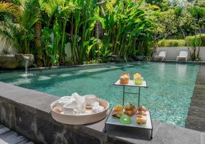a tray of food sitting next to a swimming pool at D'Green Kuta Managed by ARM Hospitality in Legian