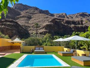 a swimming pool with a mountain in the background at SUNNY CARMELITO DELUXE in Mogán