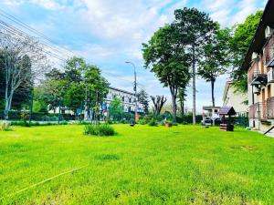 einen Hof mit grünem Gras, Gebäuden und Bäumen in der Unterkunft Hotel Hermes in Eforie Nord