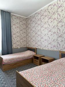 two beds in a room with floral wallpaper at Sunny Hostel in Osh