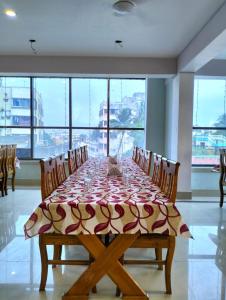 a dining room with a table with chairs and windows at Hotel Saan in Baharampur