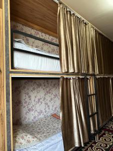 two bunk beds with curtains in a room at Sunny Hostel in Osh