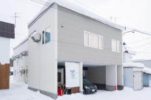 Un bâtiment blanc avec un garage dans la neige dans l'établissement The Peak Villa Suite Hokkaido, à Higashikawa