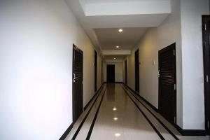 un pasillo vacío con puertas negras y paredes blancas en The Season Airport Udonthani, en Udon Thani