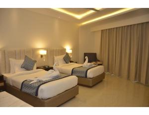 a hotel room with two beds and a couch at MJ Aero Suites, Joly Grant in Dehradun