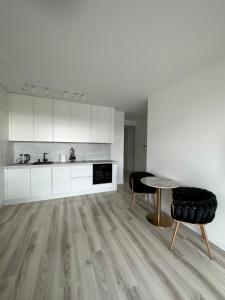 a kitchen with white cabinets and a table and chairs at Ein Park Apartment with free parking in Bratislava