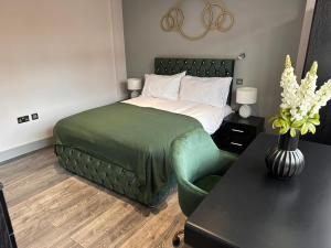 a bedroom with a bed and a green chair at Letzi Private En-Suite In Harrow in Pinner