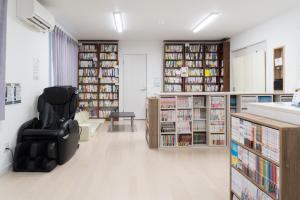 eine Bibliothek mit einem schwarzen Stuhl in der Mitte eines Zimmers in der Unterkunft The Peak Villa Suite Hokkaido in Higashikawa