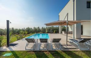 a swimming pool with four chairs and an umbrella at Villa Auri in Pula