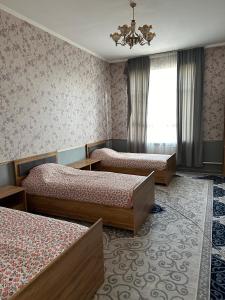 a hotel room with three beds and a chandelier at Sunny Hostel in Osh