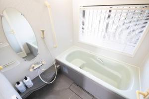 a bathroom with a tub and a sink and a mirror at 所沢レイクサイドハウス in Higashiyamato