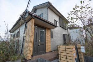 mały ceglany dom z czarnymi drzwiami w obiekcie 所沢レイクサイドハウス w mieście Higashiyamato