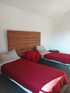 a bedroom with two beds with red sheets and a headboard at Palm Tree Room 1 in Prato