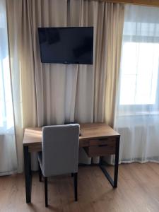 einen Holzschreibtisch mit einem Stuhl und einem TV darüber in der Unterkunft Hotel Weismann in Sankt Georgen im Attergau