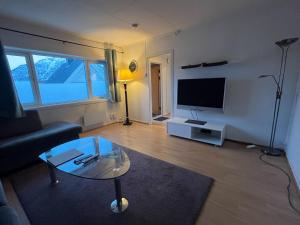 a living room with a glass coffee table and a tv at Enter Backpack Apartments in Tromsø