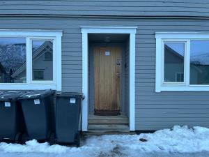 una casa con una puerta de madera y dos cubos de basura en Enter Backpack Apartments en Tromsø