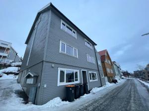 a gray house on a street in the snow at Enter Backpack Apartments in Tromsø