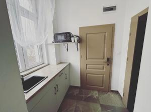 a small kitchen with a sink and a door at Apartamenty Retro in Dąbrowa Górnicza