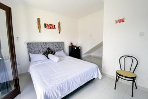 a bedroom with a white bed and a chair at Kana Guest House Mitra RedDoorz in Uluwatu