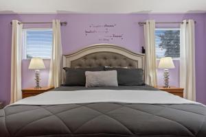 1 Schlafzimmer mit einem großen Bett mit lila Wänden und 2 Fenstern in der Unterkunft Villa Eman 5bed 4bath with Private pool& Hot Tub close 2 Disney & Legoland in Haines City + 63 Fotos