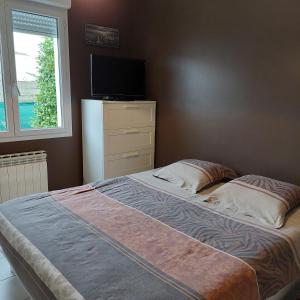 a bedroom with a bed with a television and a dresser at Villa piscine proche plages in Angresse +23 photos