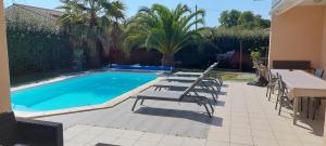 a swimming pool with chairs and a table and a table and sidx sidx at Villa piscine proche plages in Angresse