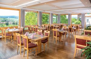 een eetkamer met tafels en stoelen en grote ramen bij Hotel Sonnentau in Fladungen