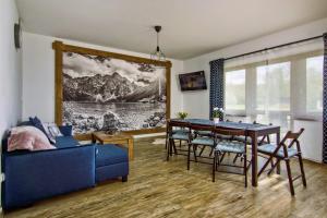 a living room with a dining table and a blue couch at Magia Gór -500m do Gorący Potok i Term Szaflary-rabaty in Szaflary